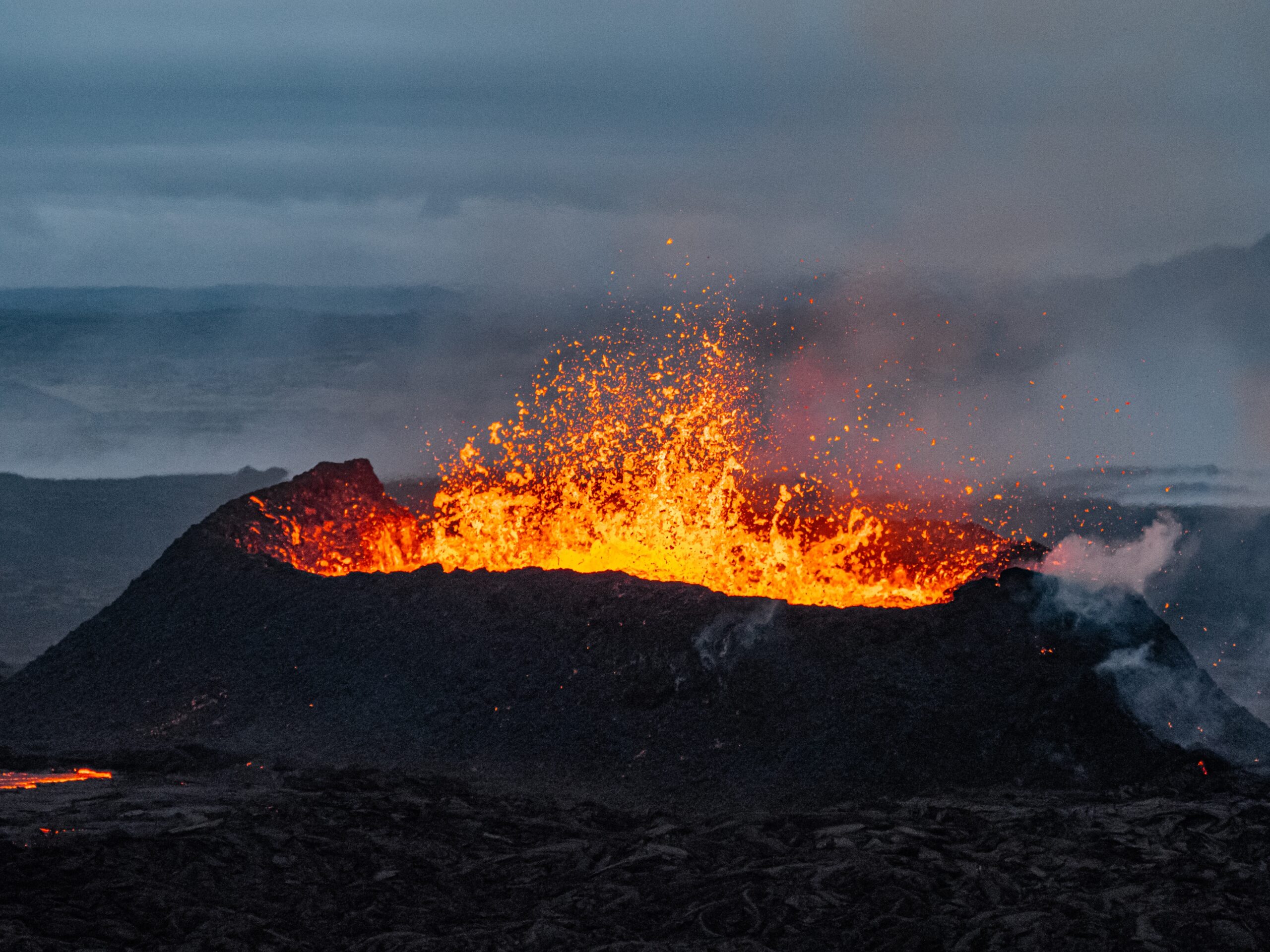 Ein Vulkan bricht aus und spritzt mit Lava.