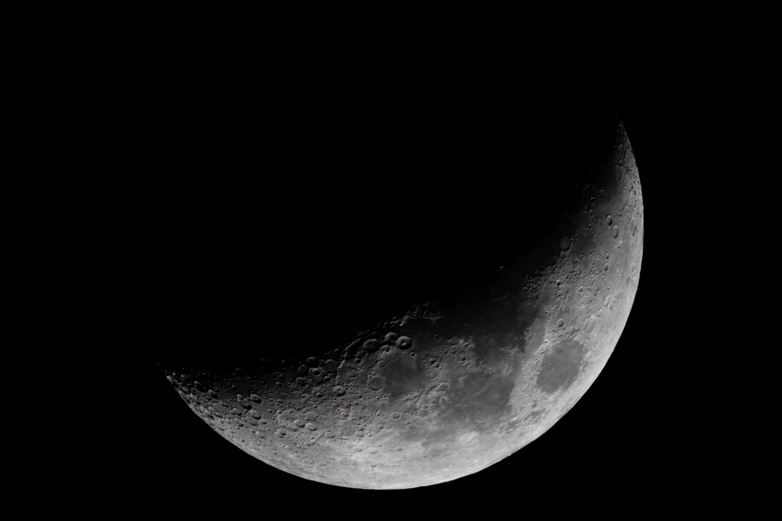 Der Mond ist halb beleuchtet und man sieht viele Krater.